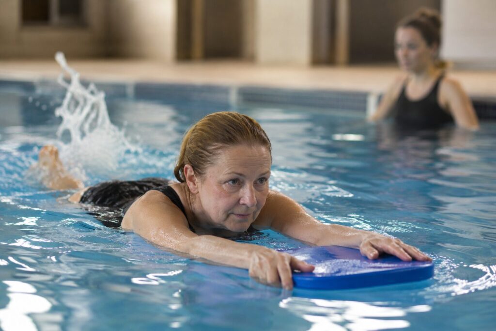 Adult beginner learning to swim with a kickboard during a lesson