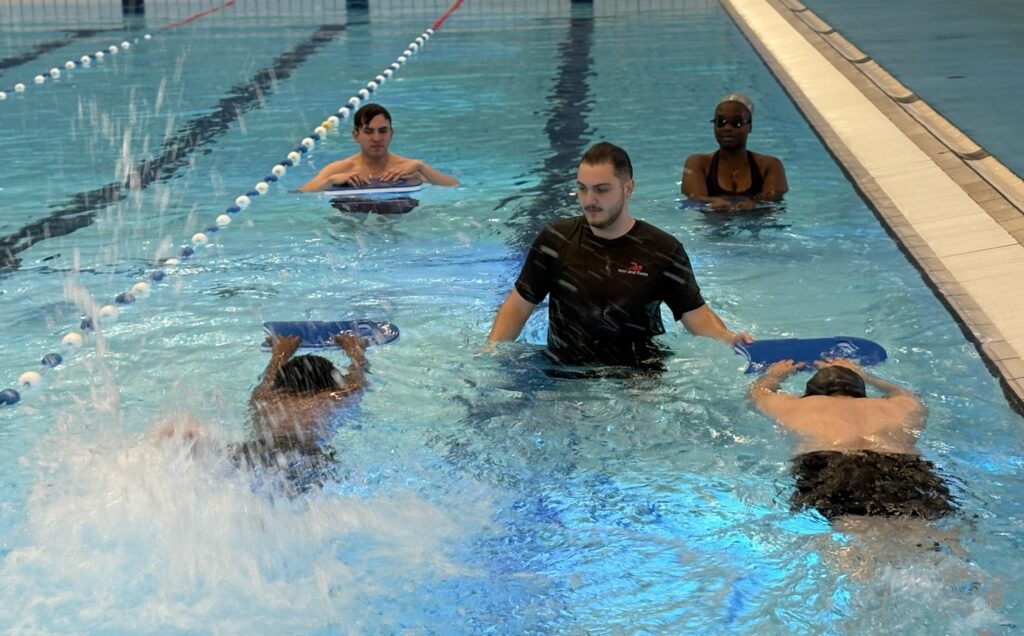 Coach David helps swimmers learn to do freestyle kicks with the board