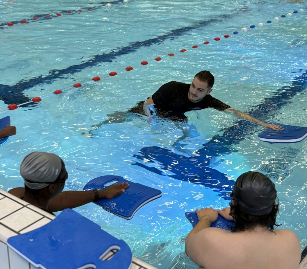 Coach David showing beginner swimmers the freestyle technique in Friendship Sport Center