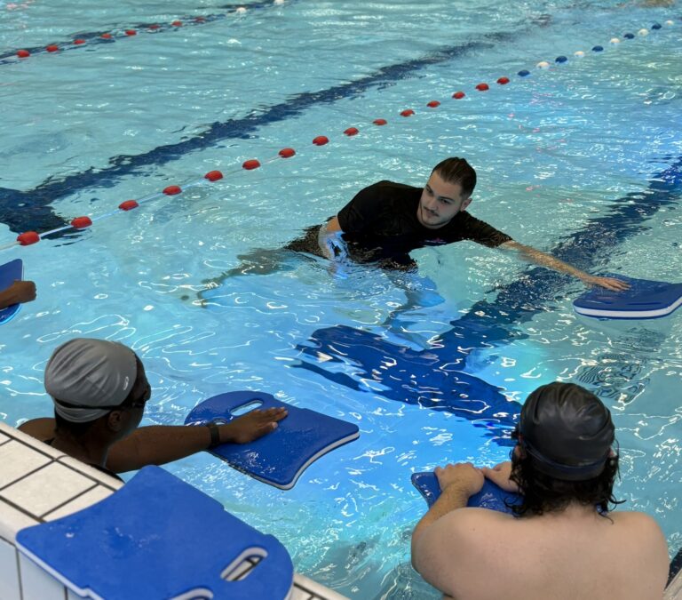 Coach David showing beginner swimmers the freestyle technique in Friendship Sport Center